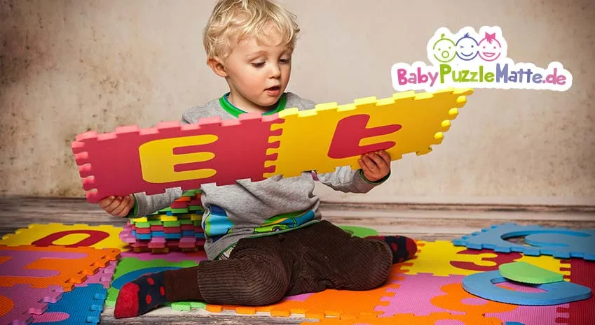Kind spielt und lernt mit Puzzlematte Buchstaben