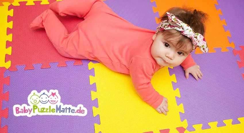 Puzzlematte mit Baby, das über die bunten Puzzle Felder krabbelt