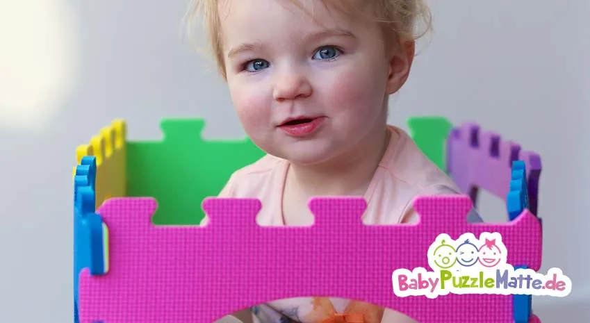 Kleinkind spielt mit seiner Puzzlematte rosa