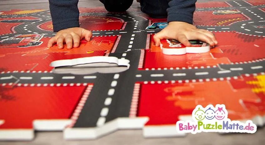 Kind spielt auf einer Puzzlematte Straße Motiv